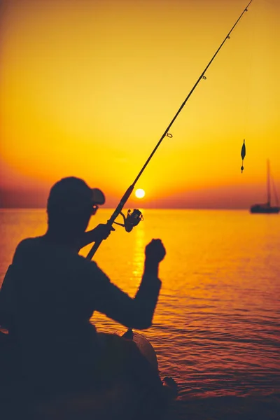 Silhouette d'un pêcheur pêchant au coucher du soleil en pleine mer — Photo