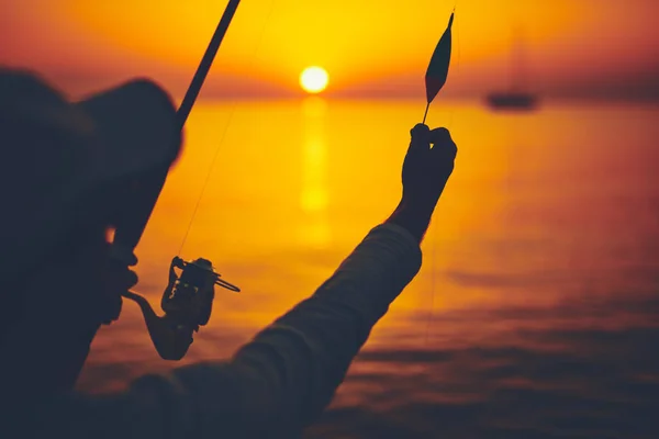 Silhueta de um pescador pescando em tempo de pôr do sol no mar aberto — Fotografia de Stock