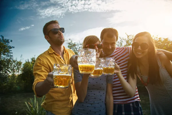 Grupo de jóvenes disfrutando y animando la cerveza al aire libre . — Foto de Stock