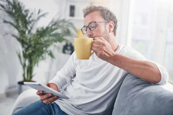 Hombre sosteniendo la tableta, navegar en línea y beber café . — Foto de Stock