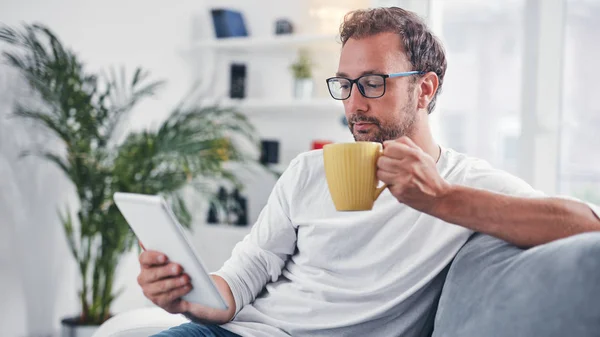 Hombre sosteniendo la tableta, navegar en línea y beber café . — Foto de Stock
