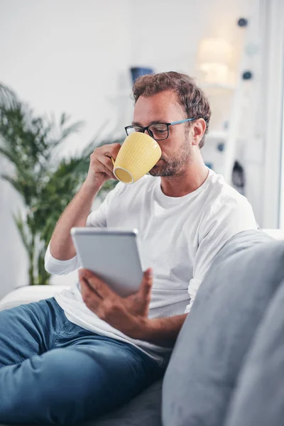 Hombre sosteniendo la tableta, navegar en línea y beber café . — Foto de Stock