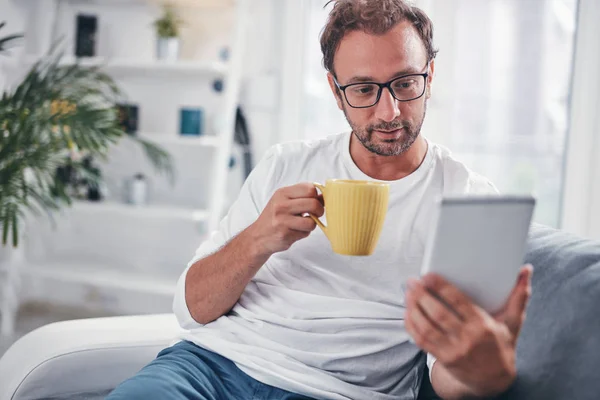 Hombre sosteniendo la tableta, navegar en línea y beber café . — Foto de Stock