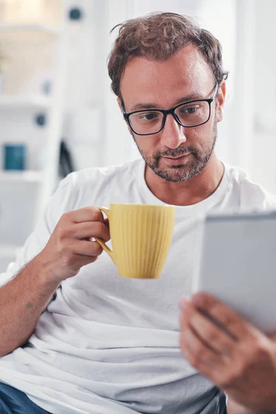 Hombre sosteniendo la tableta, navegar en línea y beber café . — Foto de Stock