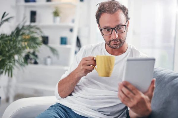 Hombre sosteniendo la tableta, navegar en línea y beber café . — Foto de Stock