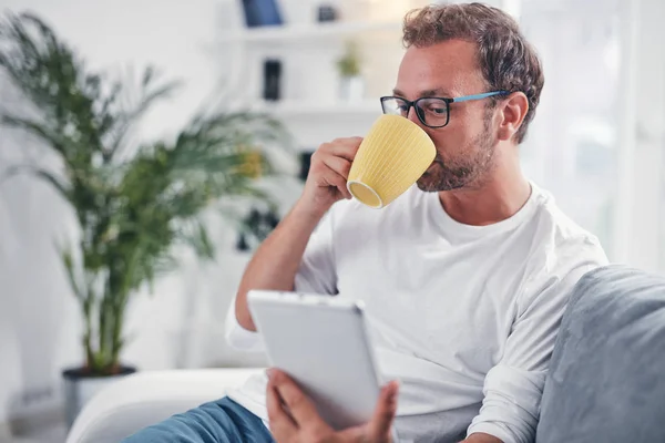 Hombre sosteniendo la tableta, navegar en línea y beber café . — Foto de Stock