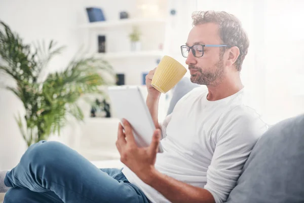 Hombre sosteniendo la tableta, navegar en línea y beber café . — Foto de Stock