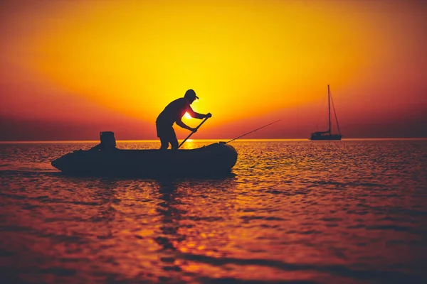 Silhouette di un pescatore che pesca al tramonto in mare aperto — Foto Stock