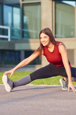 Şehir parkında egzersiz yapan / esneyen genç bir kadın..