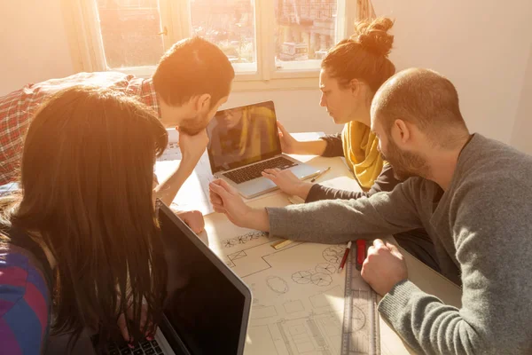 Equipo formado por jóvenes arquitectos en la soleada oficina . — Foto de Stock