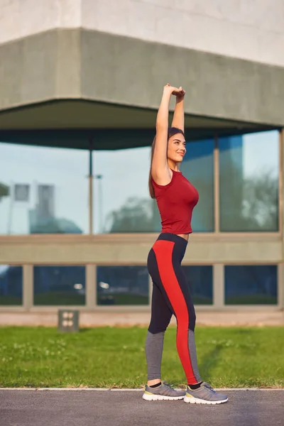 Jeune femme faisant de l'exercice / s'étirant dans un parc urbain . — Photo