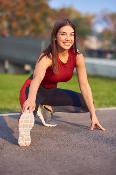 Jeune femme faisant de l'exercice / s'étirant dans un parc urbain . — Photo