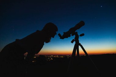 Teleskopla gökbilimci yıldızları ve Ay 'ı izliyor. 