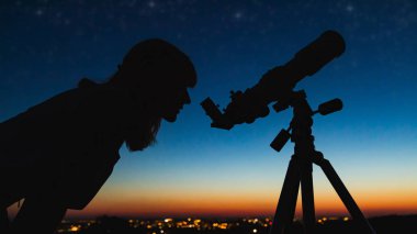 Teleskopla gökbilimci yıldızları ve Ay 'ı izliyor. 