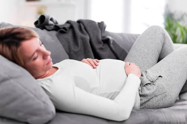 Pregnant tired exhausted woman with stomach issues at home on a — 스톡 사진