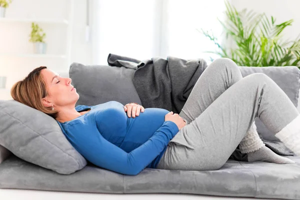 Těhotná unavená žena s žaludečními potížemi doma na — Stock fotografie