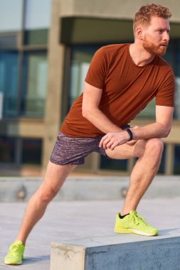 Genç adam şehir parkında egzersiz yapıyor / esniyor.