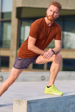 Genç adam şehir parkında egzersiz yapıyor / esniyor.