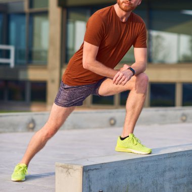 Genç adam şehir parkında egzersiz yapıyor / esniyor.