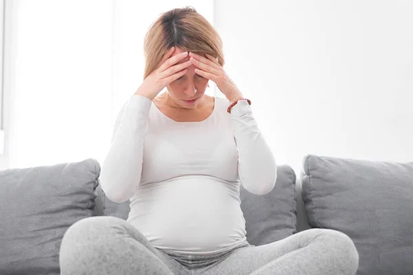 Zwanger vermoeide, vermoeide vrouw met maag- en hoofdproblemen bij h — Stockfoto