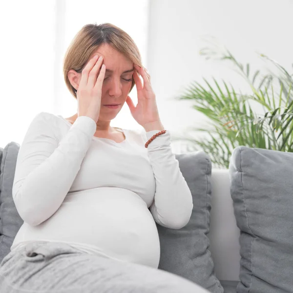 Embarazada cansada mujer agotada con problemas de estómago y cabeza en h —  Fotos de Stock