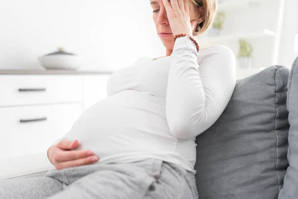 Zwanger vermoeide, vermoeide vrouw met maag- en hoofdproblemen bij h — Stockfoto