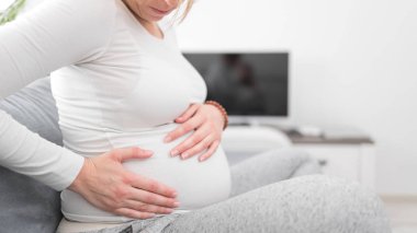 Pregnant tired exhausted woman with stomach issues at home on a 