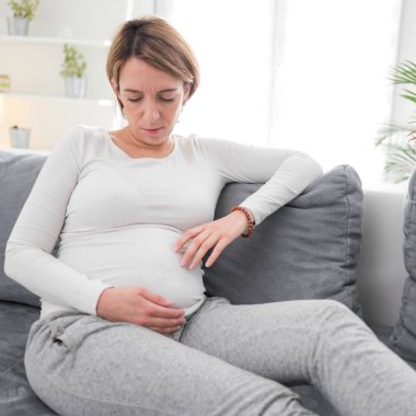 Pregnant tired exhausted woman with stomach issues at home on a 
