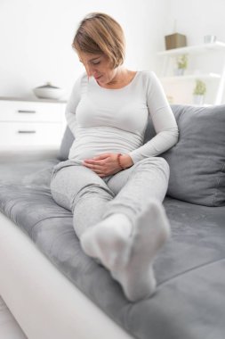 Pregnant tired exhausted woman with stomach issues at home on a 