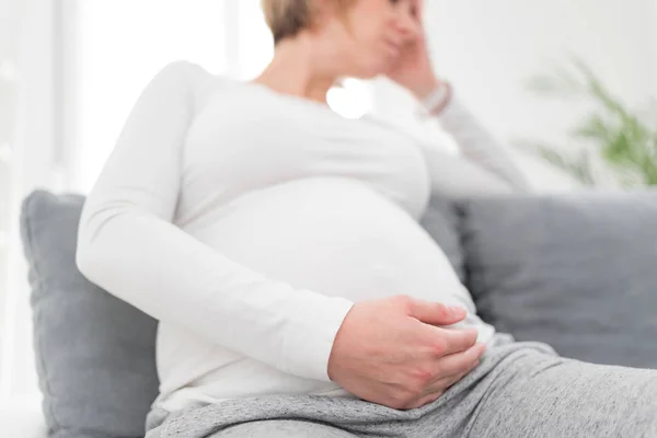 Zwanger vermoeide, vermoeide vrouw met maag- en hoofdproblemen bij h — Stockfoto