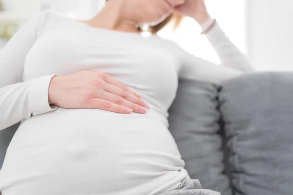 Zwanger vermoeide, vermoeide vrouw met maag- en hoofdproblemen bij h — Stockfoto