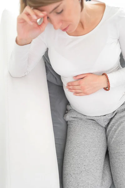 Zwanger vermoeide, vermoeide vrouw met maag- en hoofdproblemen bij h — Stockfoto