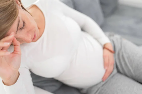 Zwanger vermoeide, vermoeide vrouw met maag- en hoofdproblemen bij h — Stockfoto