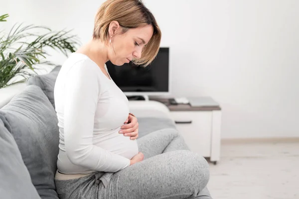 Zwanger vermoeide vermoeide vrouw met maagproblemen thuis op een — Stockfoto