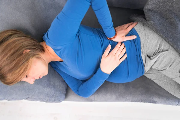 Mujer cansada y cansada embarazada con problemas estomacales y dolor de espalda —  Fotos de Stock