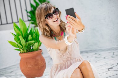 Sevimli genç kadın sokakta cep telefonu kullanarak.