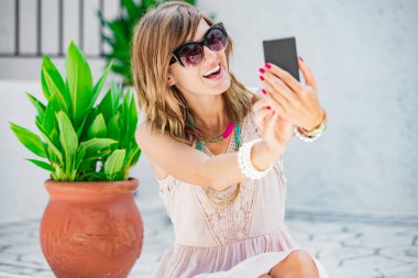 Sevimli genç kadın sokakta cep telefonu kullanarak.