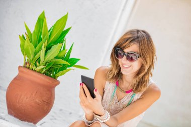 Sevimli genç kadın sokakta cep telefonu kullanarak.