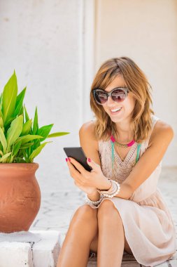 Sevimli genç kadın sokakta cep telefonu kullanarak.