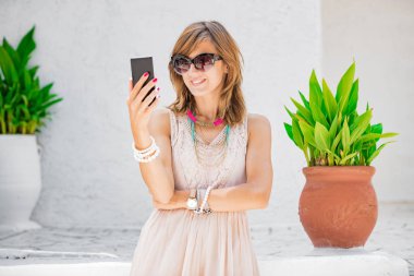 Sevimli genç kadın sokakta cep telefonu kullanarak.