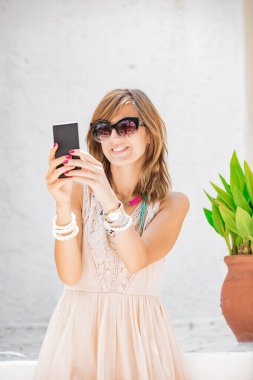 Sevimli genç kadın sokakta cep telefonu kullanarak.