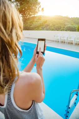 Yüzme havuzu yakınında cep telefonu kullanan genç kadın.
