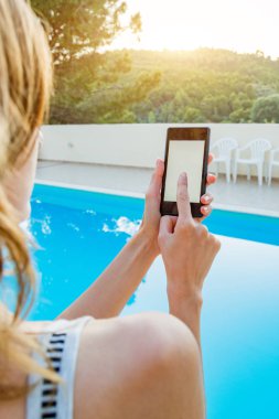 Yüzme havuzu yakınında cep telefonu kullanan genç kadın.