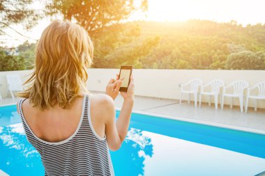 Yüzme havuzu yakınında cep telefonu kullanan genç kadın.