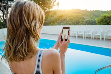 Yüzme havuzu yakınında cep telefonu kullanan genç kadın.