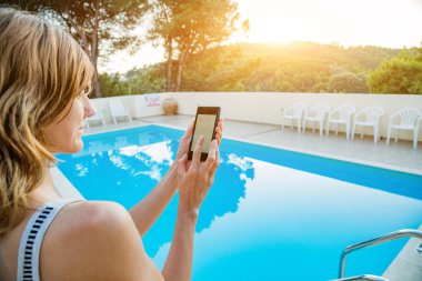 Yüzme havuzu yakınında cep telefonu kullanan genç kadın.