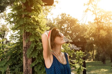 Yaz güneşinde dışarıda poz veren sevimli genç bir kadın..
