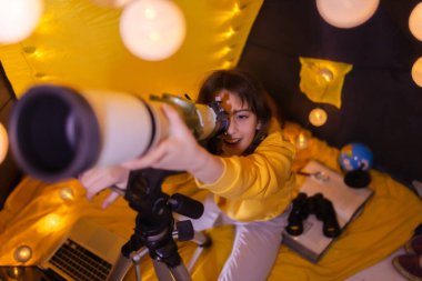 Küçük bir kız çadırda teleskop kullanıyor..