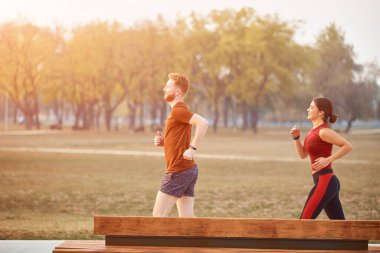 Modern kadın ve erkek şehir parkında koşuyor / egzersiz yapıyor.