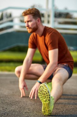 Genç adam şehir parkında egzersiz yapıyor / esniyor.